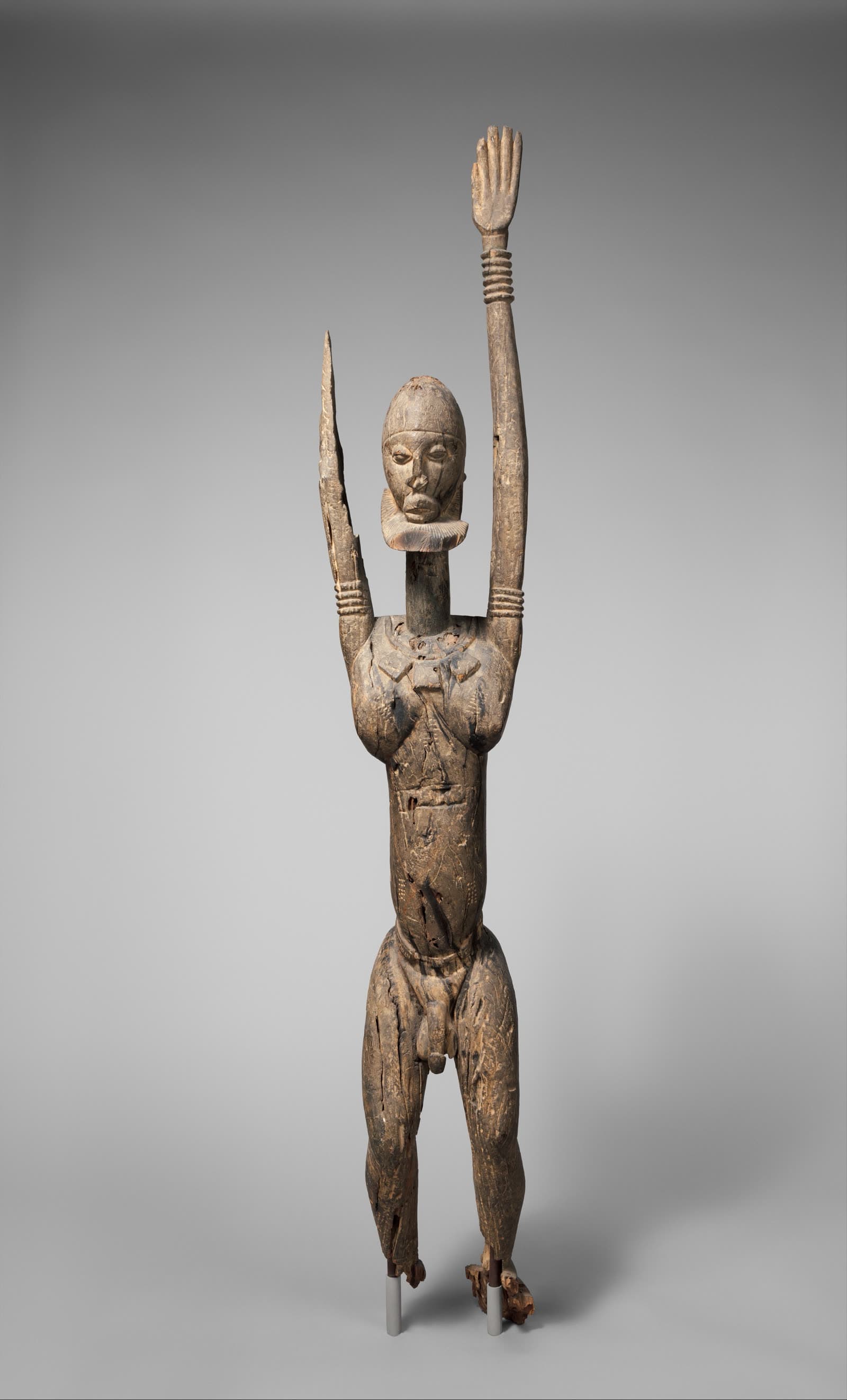 A wood figure with raised arms, identified by the Metropolitan Museum of Art as Dogon peoples.